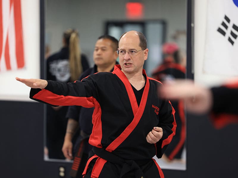 Adult martial arts participants kicking pads during stress-relief workout session